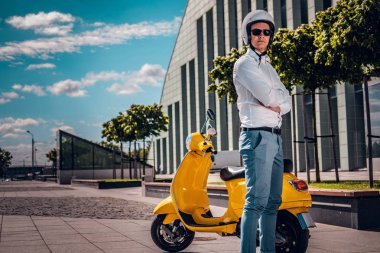 Yakışıklı adam kask ve kollarını bir scooter Street yanında çarpı işareti ile poz güneş gözlüğü