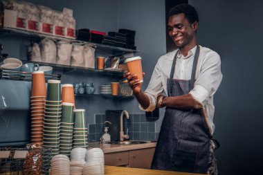 Bir fincan kahve bir kafede elinde tutan Afrika barista bakar