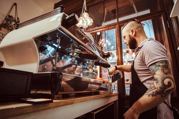 Barista en delantal haciendo un capuchino, vertiendo leche en taza de acero en un restaurante o cafetería — Foto de Stock