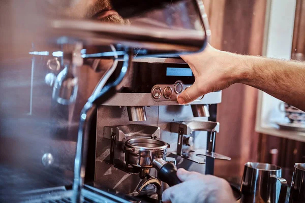 Barista sosteniendo un portafilter con un café negro molido y trabajando en una máquina de café en una cafetería o restaurante —  Fotos de Stock