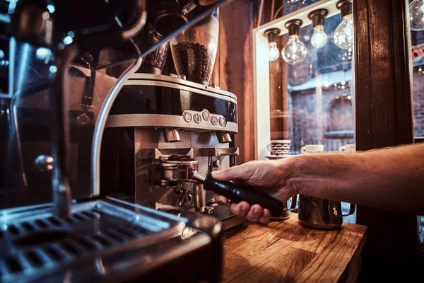 Barista sosteniendo un portafilter con un café negro molido en una cafetería o restaurante —  Fotos de Stock