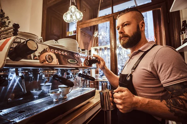 Barista tatuado con barba elegante y peinado trabajando en una máquina de café en una cafetería o restaurante —  Fotos de Stock