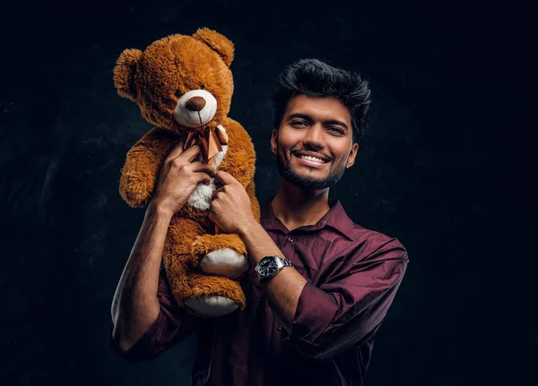 Indiase jongeman in stijlvol shirt teddybeer houden en kijken naar een camera glimlachen. — Stockfoto
