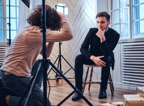 Fotoshooting im Studio: Ein gutaussehender junger Kerl sitzt, lächelt und posiert — Stockfoto