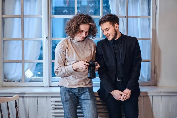 Fotógrafo hombre mostrando fotos en cámara digital para adaptarse a custumer vestido — Foto de Stock