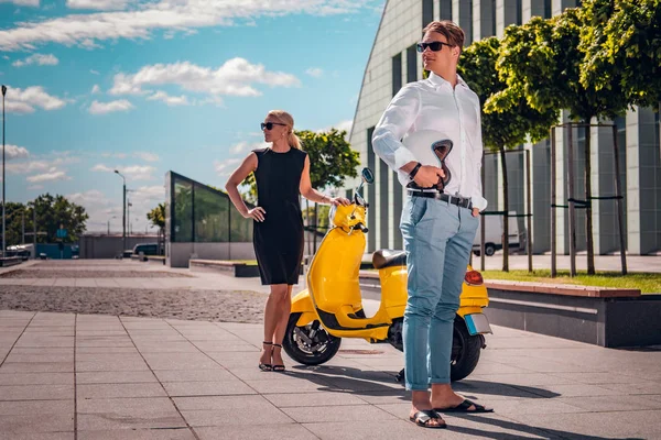 Jong koppel poseren naast een klassieke Italiaanse scooter op de straat — Stockfoto