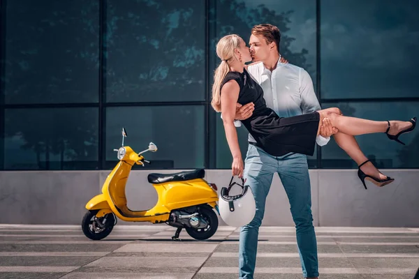 Romantische verliefde paar, een kerel kussen zijn vriendin haar op zijn handen terwijl staande te houden op een wolkenkrabber in het centrum van de stad — Stockfoto