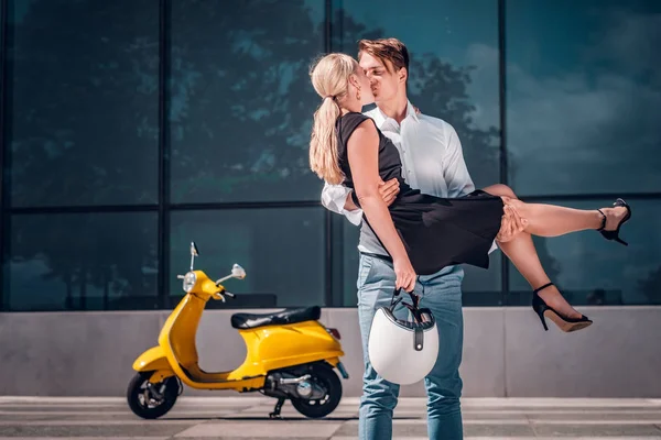 Casal romântico apaixonado, um cara beija sua namorada segurando-a em suas mãos enquanto está em um arranha-céu no centro da cidade — Fotografia de Stock