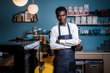 Barista ayakta kolları geçti ve bir kamera bir kafede bakarak
