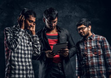 Üç adam koyu tenli bir tablet ve kulaklık ile müzik dinlemek
