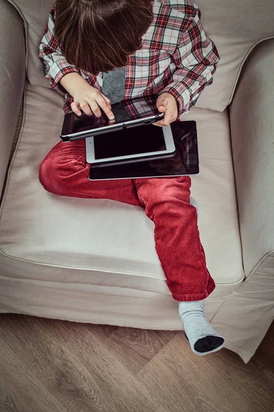 Kaukasischer Schüler im karierten Hemd mit Krawatte sitzt mit einem digitalen Tablet auf einer Couch zu Hause — Stockfoto