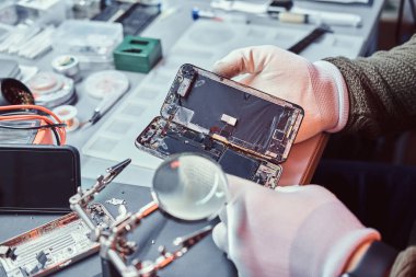 Teknisyen dikkatle smartphone içinde modern bir tamirciye iç unsurları bütünlüğünü inceler