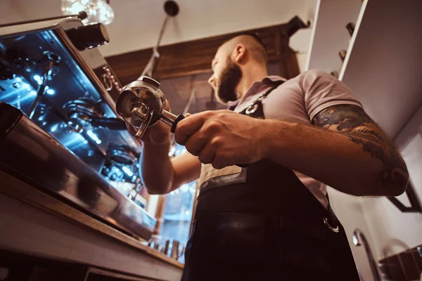 Foto de baixo ângulo de um barista segurando um portafilter, trabalhando na cafeteria — Fotografia de Stock
