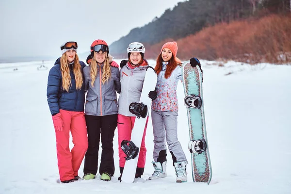 Veselé ženy přátelé v sportovní zimní oblečení, snowboardy a lyže, které představují — Stock fotografie