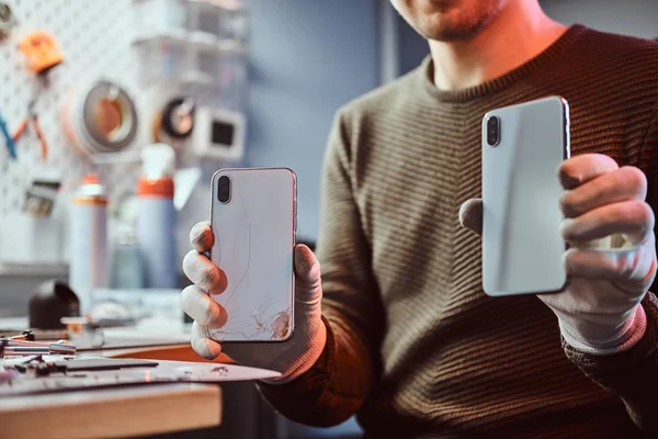 Technician holds two identical smartphones for comparison, in one hand broken and in another new — Stock Photo, Image