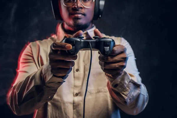 Foto ritagliata di un giocatore dalla pelle scura con cuffie e un joystick di gioco — Foto Stock