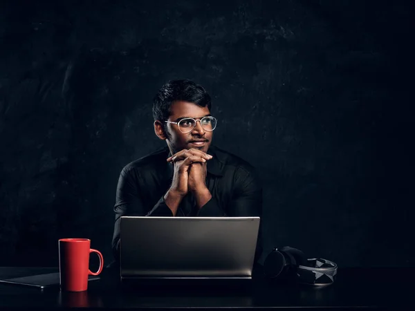 Portrait of a dark skinned freelancer sitting at a desk with a laptop — Stock Photo, Image