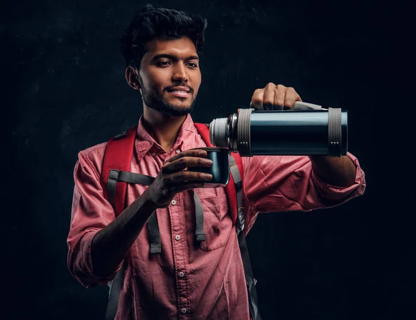 Jovem caminhante indiano derrama seu próprio chá de uma garrafa térmica . — Fotografia de Stock