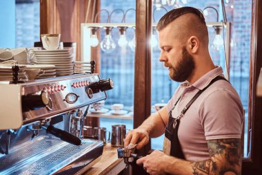Bir kafede kapuçino hazırlamadan önce bir barista yan görünüm portafilter temizler