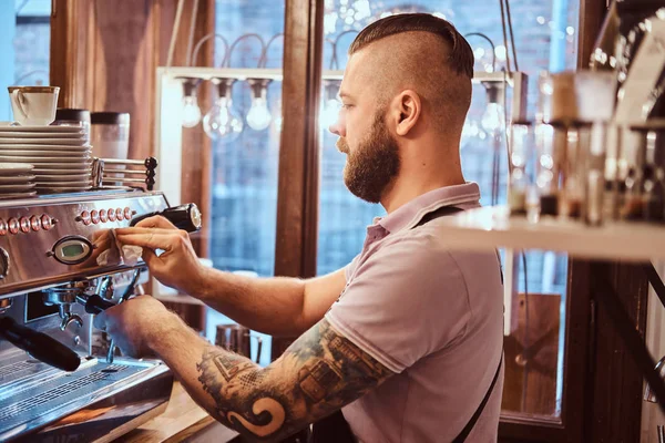 Dövmeli barista şık sakal ve saç modeli bir kafe ya da Restoran bir kahve makinesinde çalışma ile