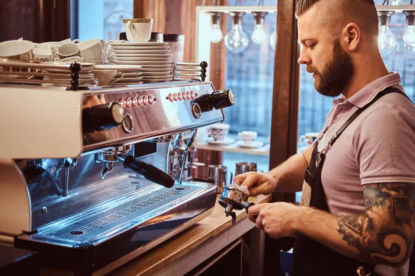 Oldalnézetből egy barista tisztítja az őrleményt a szűrőbetétben a cappuccino egy kávézóban elkészítése előtt — Stock Fotó