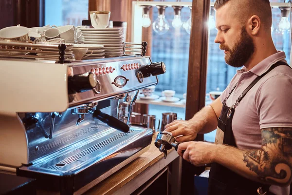 Vista lateral de un barista limpia el portafilter antes de preparar el capuchino en una cafetería —  Fotos de Stock