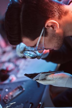 Teknisyen dikkatle smartphone içinde modern bir tamirciye iç unsurları bütünlüğünü inceler