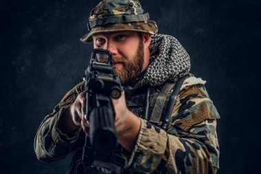Özel Kuvvetler asker bir saldırı tüfeği tutan askeri kamuflaj üniformalı. Studio fotoğraf bir karanlık dokulu duvara