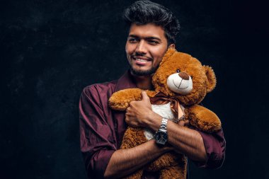 Oyuncak ayı ve yana doğru seyir yakışıklı genç Hintli şık gömlek hugs.