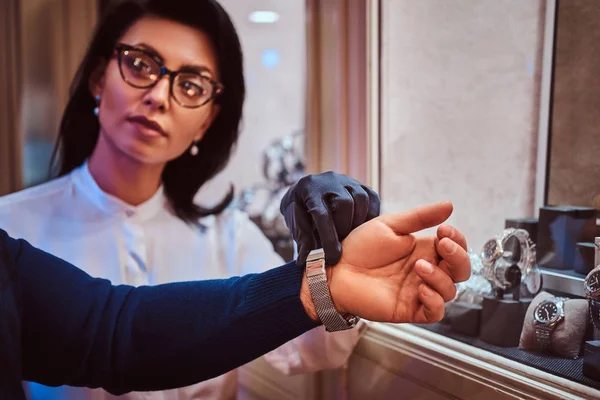 Mulher assistente vestidos exclusivos mens relógios na mão clientes na joalharia — Fotografia de Stock