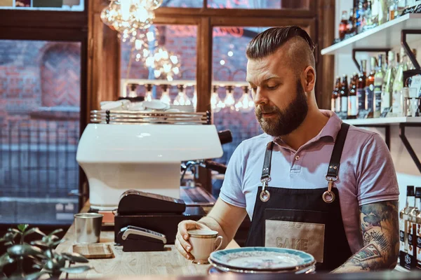 Barista di celemek minum kopi selama istirahat makan siang berdiri di belakang meja di kedai kopi — Stok Foto