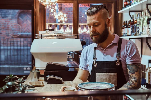 Barista di celemek minum kopi selama istirahat makan siang berdiri di belakang meja di kedai kopi — Stok Foto