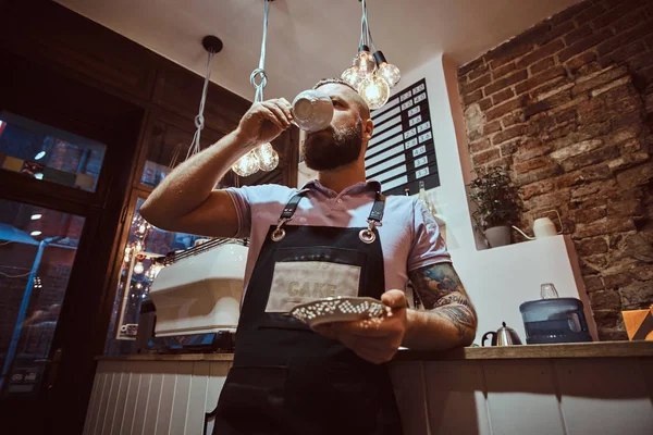 Yakışıklı barista kahve dükkanında bir sayaçta eğilerek öğle yemeği molası sırasında kahve içme önlük — Stok fotoğraf