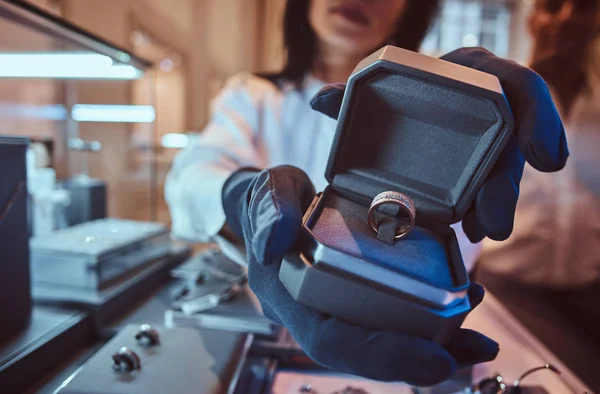 Ассистентка показывает эксклюзивное золотое кольцо в ювелирном магазине — стоковое фото