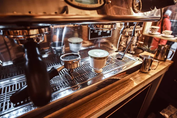 Primer plano de un portafilter y taza con capuchino junto a una máquina de café en el restaurante de una cafetería —  Fotos de Stock
