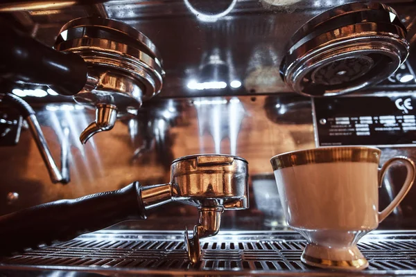 Nahaufnahme eines Portafilters und einer Tasse mit Cappuccino neben einer Kaffeemaschine im Restaurant eines Cafés — Stockfoto