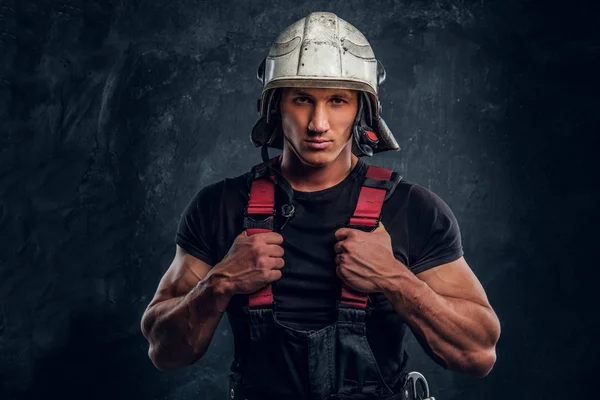 Retrato de un hombre guapo con un casco de fuego y guantes, mirando a una cámara — Foto de Stock