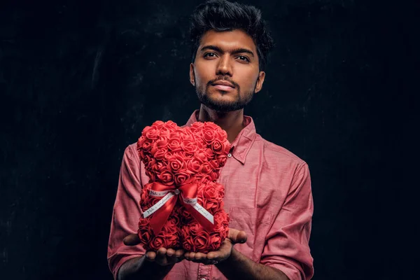 Indiase man in een roze shirt heeft een mooi geschenk te kijken naar de camera. Romantische stemming, liefdesrelatie. — Stockfoto