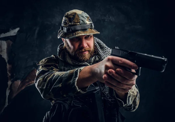 Homem brutal no uniforme camuflado militar segurando uma arma e apontando para o inimigo . — Fotografia de Stock