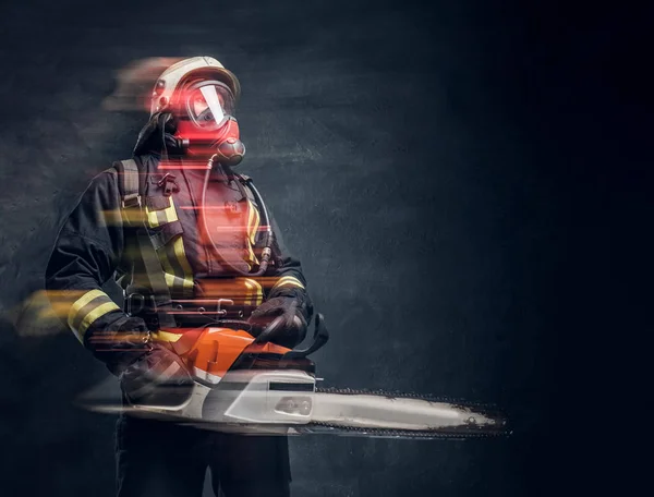 Retrato de um bombeiro em capacete de segurança e máscara de oxigênio segurando uma motosserra. Foto do estúdio contra uma parede de textura escura — Fotografia de Stock