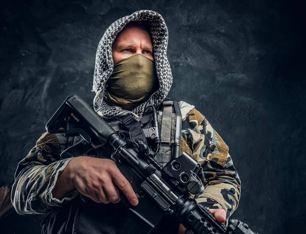 Forças especiais soldado de uniforme militar usando máscara e capuz segurando um rifle de assalto . — Fotografia de Stock