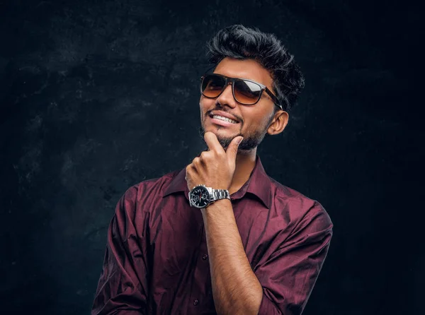 Vogue, mode, stijl. Vrolijke jonge Indiase kerel het dragen van een stijlvol shirt en zonnebril poseren met de hand op kin. — Stockfoto