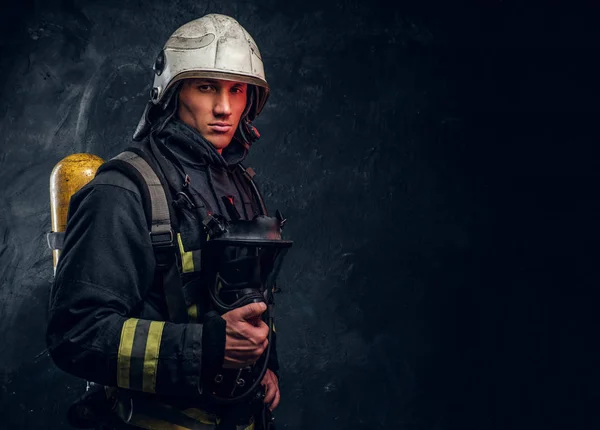 Brandweerman in volledige beschermende uitrusting een zuurstofmasker houden en kijken naar een camera. — Stockfoto