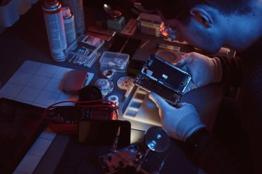 Teknisyen dikkatle smartphone içinde modern bir tamirciye iç unsurları bütünlüğünü inceler