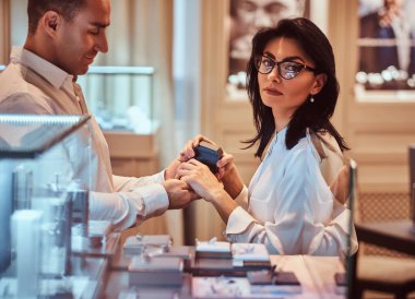 Zarif giyimli erkek ve kız arkadaşı bir kuyumcuya alyans seçin