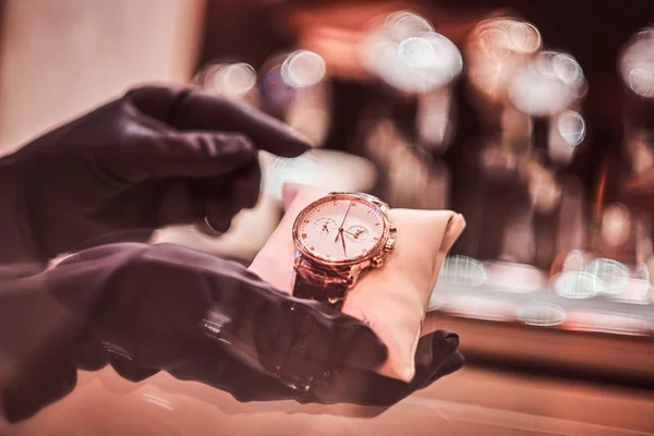 Close-up of the sellers hands in gloves shows the exclusive mens watch from the new collection — Stock Photo, Image