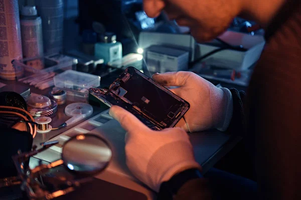 Technician carefully examines the integrity of the internal elements of the smartphone in a modern repair shop — Stock Photo, Image