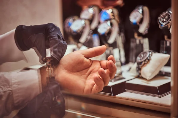 Närbild händer. Assistenten hjälper klienten att prova på exklusiva mens klockor. — Stockfoto