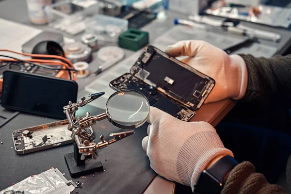Técnico examina cuidadosamente a integridade dos elementos internos do smartphone em uma oficina de reparação moderna — Fotografia de Stock