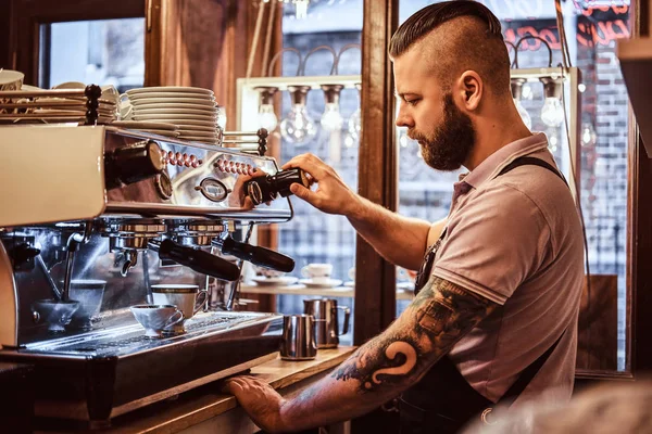 Barista de uniforme preparando uma xícara de café para um cliente no café — Fotografia de Stock